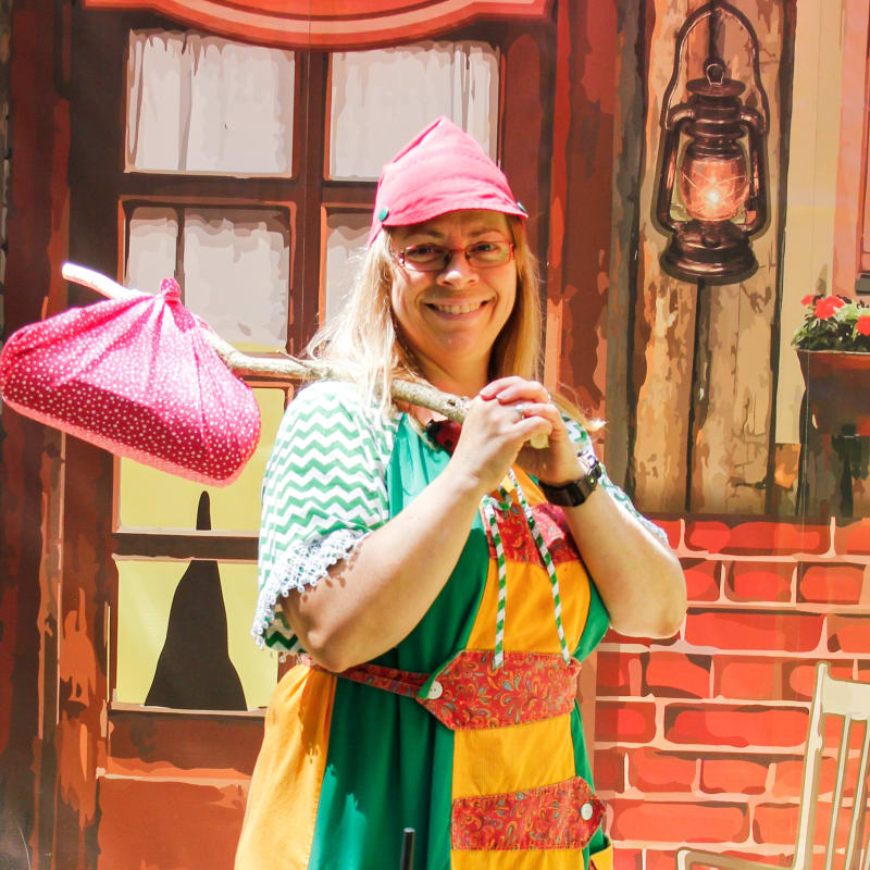 Woman carrying a bundle and wearing a fun costume at la Vallée Secrète.