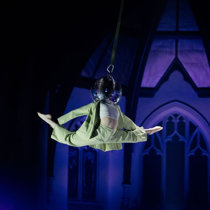 Le Monastère - Cabaret de Cirque - A suspended artist with their head in a disco ball