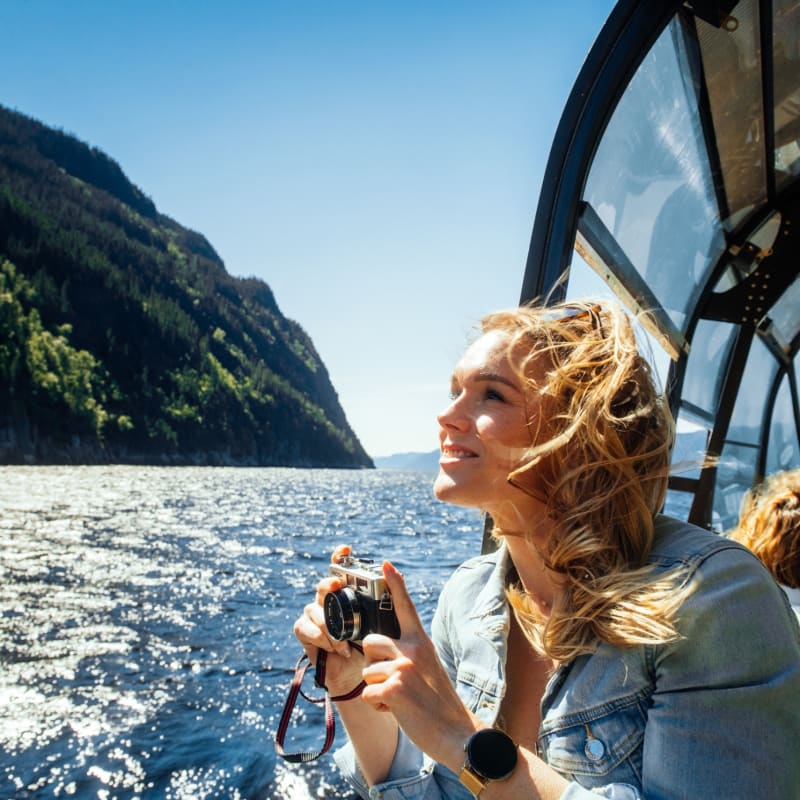 Les navettes maritimes du Fjord - A woman on a boat holding a camera.