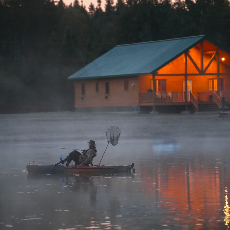 Personne sur un ponton sur le lac devant un chalet.