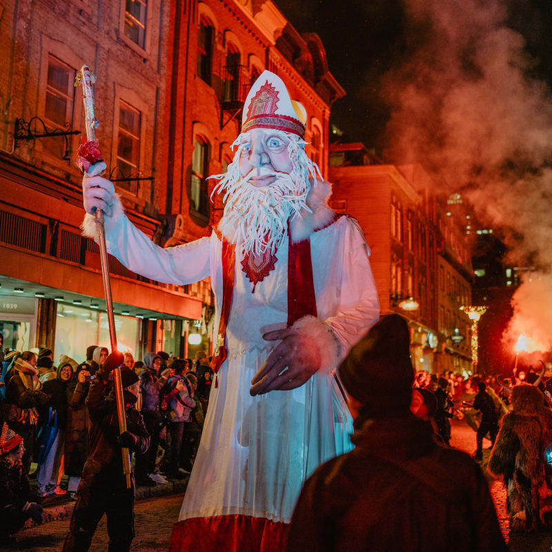 Marché de Noël allemand Québec - grande marionnette représentant le Père Noël, illuminée et se tenant au milieu d'une rue animée la nuit
