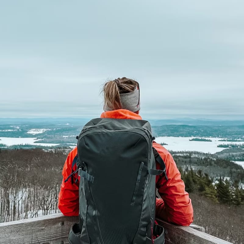 Discover Outaouais and its many areas with these must-sees! - Hiker admiring the view from a mountaintop in winter