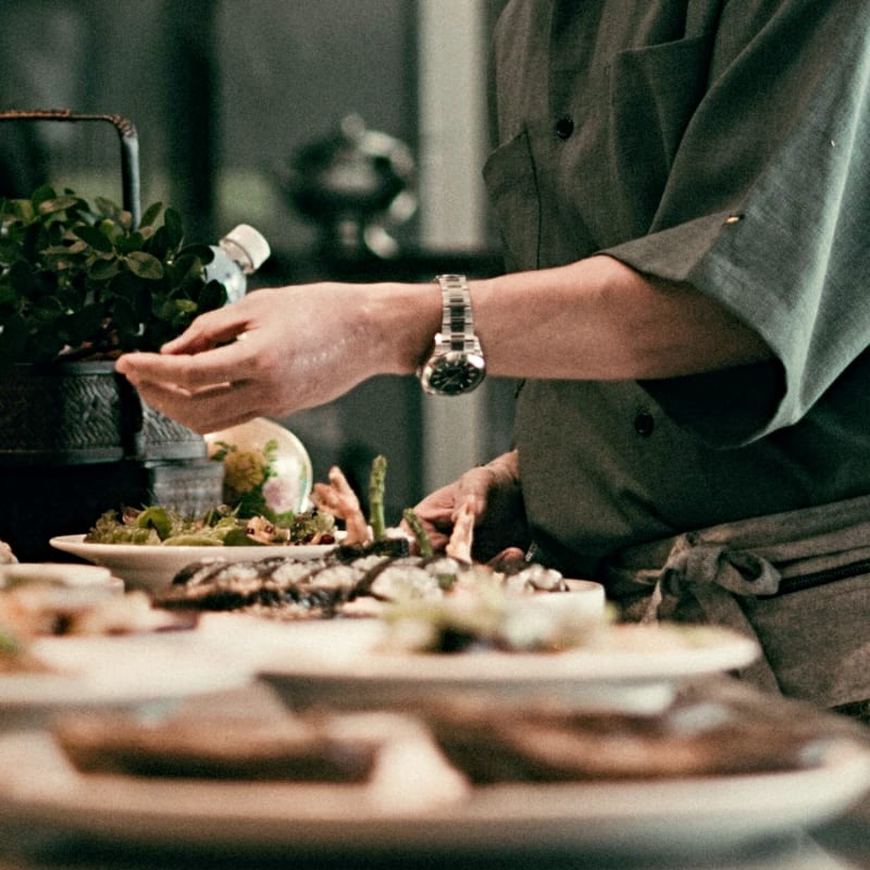 Femme assise à table devant différents plats.