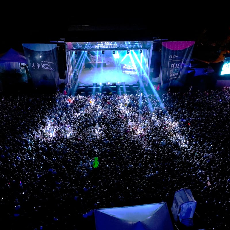 Large crowd in front of an outdoor stage at night at the Fête du Lac des Nations.