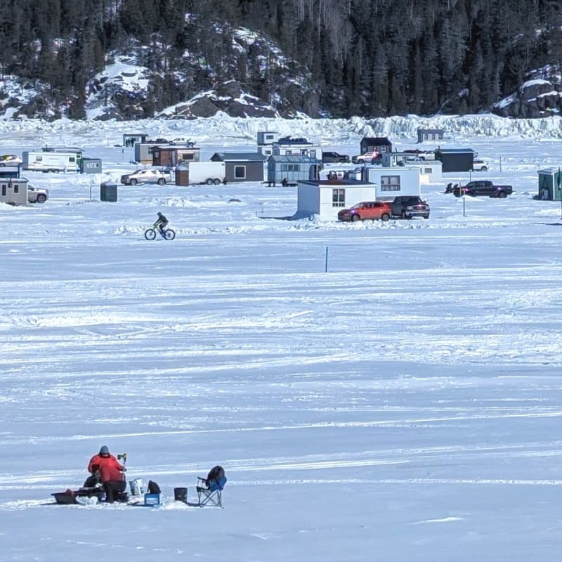 The snow-covered Saguenay Fjord and ice fishing cabins seen in the distance.