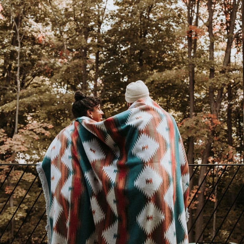 Couple in front of a forest in late fall.