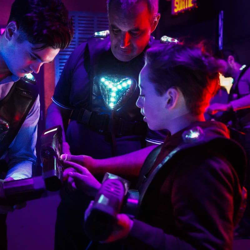 Three people wearing laser tag uniforms in a huddle.