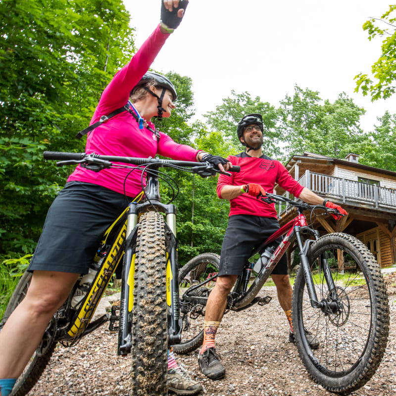 Deux cyclistes de montagne devant un chalet.