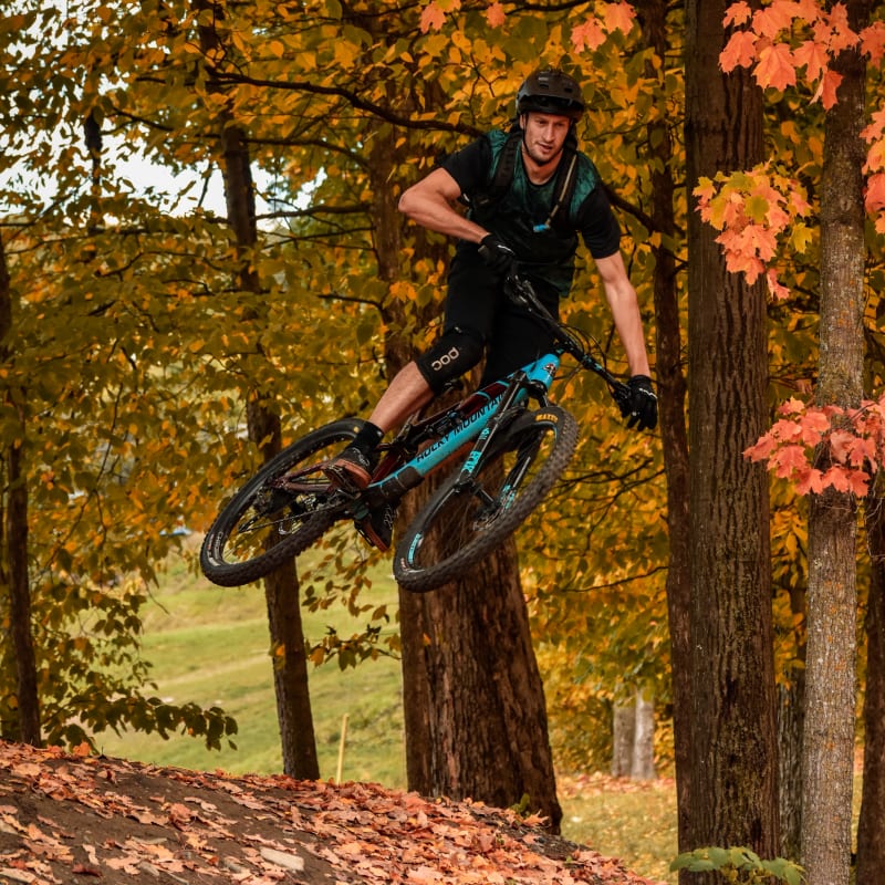 Mountain biker making a jump in a fall setting.