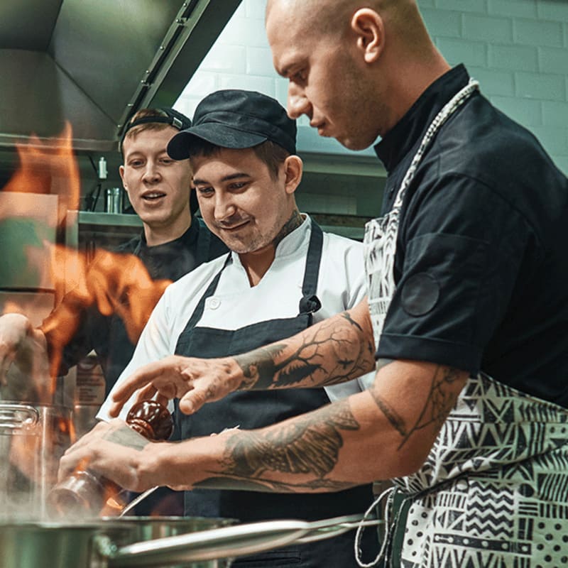 Trois hommes qui travaillent dans une cuisine industrielle.