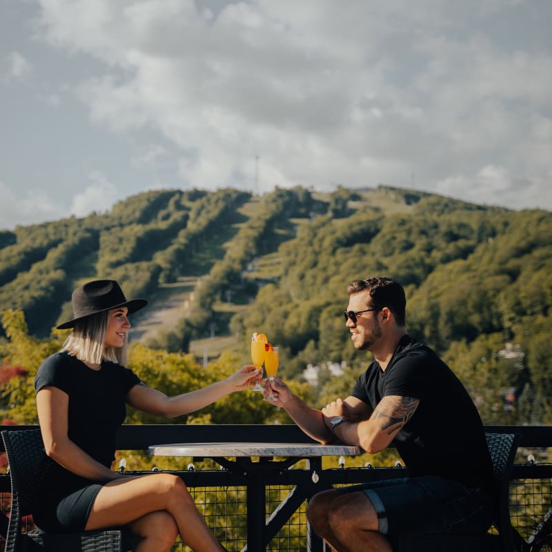 Couple sharing a drink in front of the ski hill in late summer.