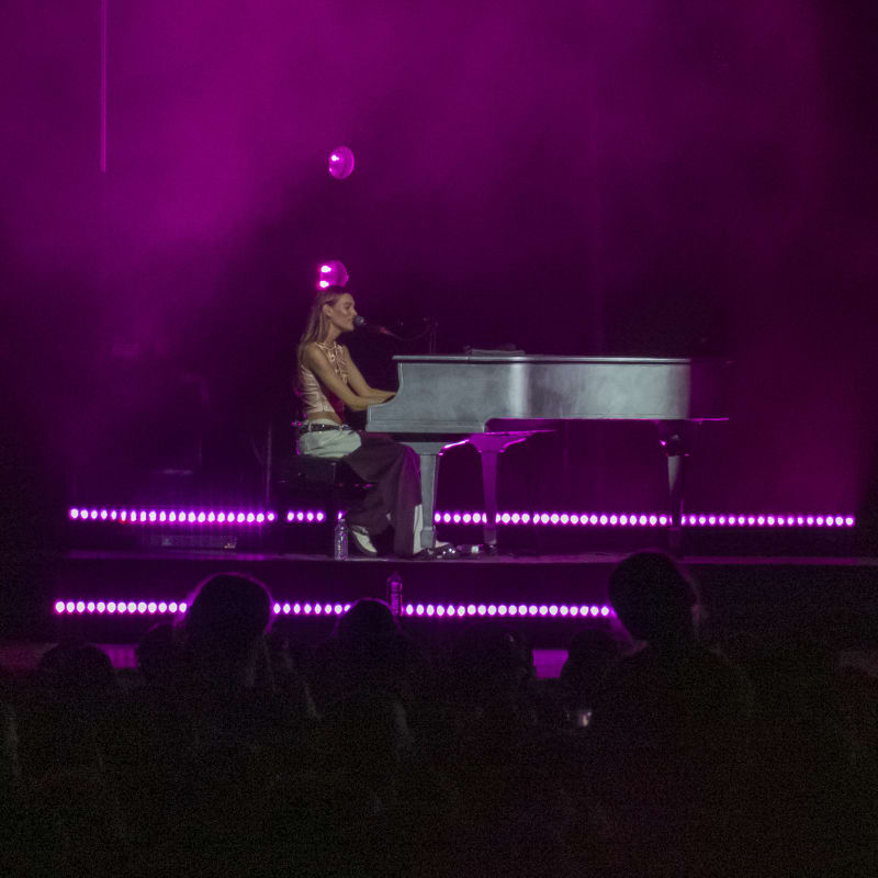 Charlotte Cardin at the piano on stage in the evening.