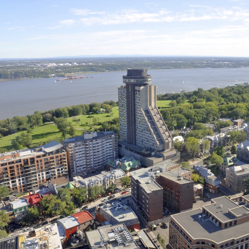 Hotel Le Concorde in Québec City seen from above with the Plains of Abraham and St. Lawrence River in the background.