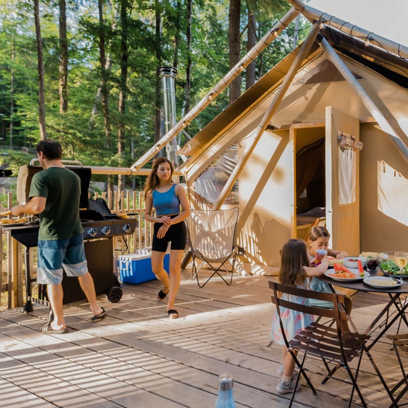 Family of four enjoying the sunshine on the terrace of their ready-to-camp tent.