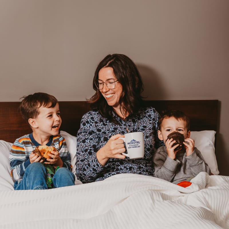 Mother and two sons having breakfast in bed at the hotel.