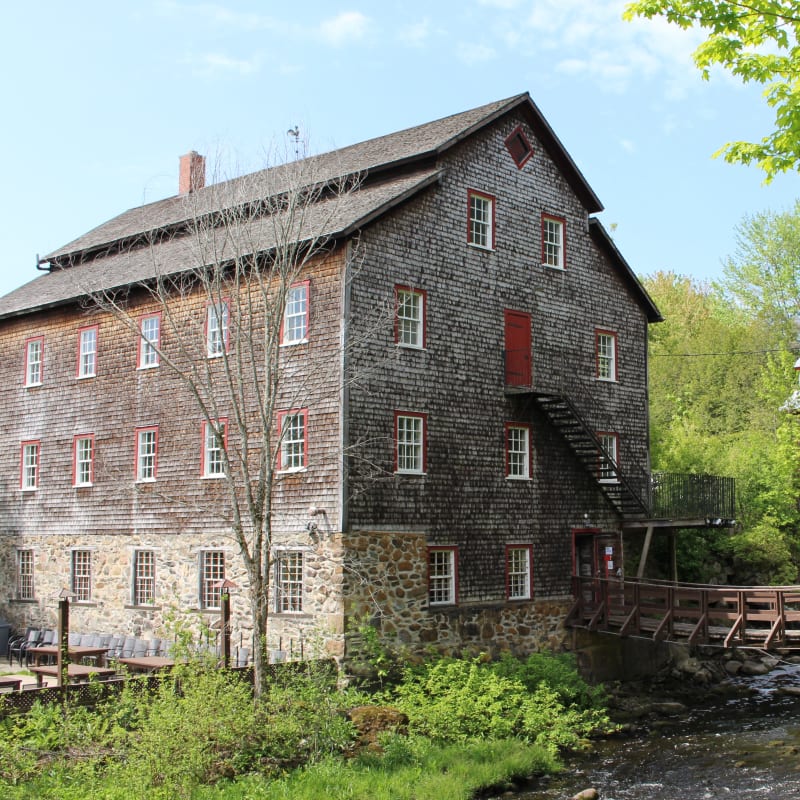 Exterior of the ancestral building, with a small wooden bridge over a stream.