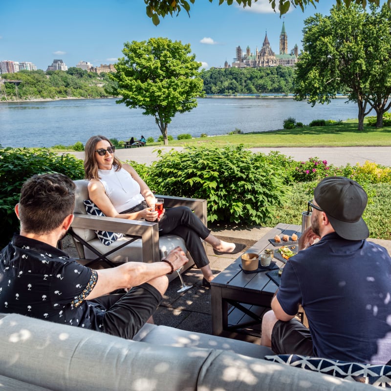4 friends on patio furniture in front of the Ottawa River.