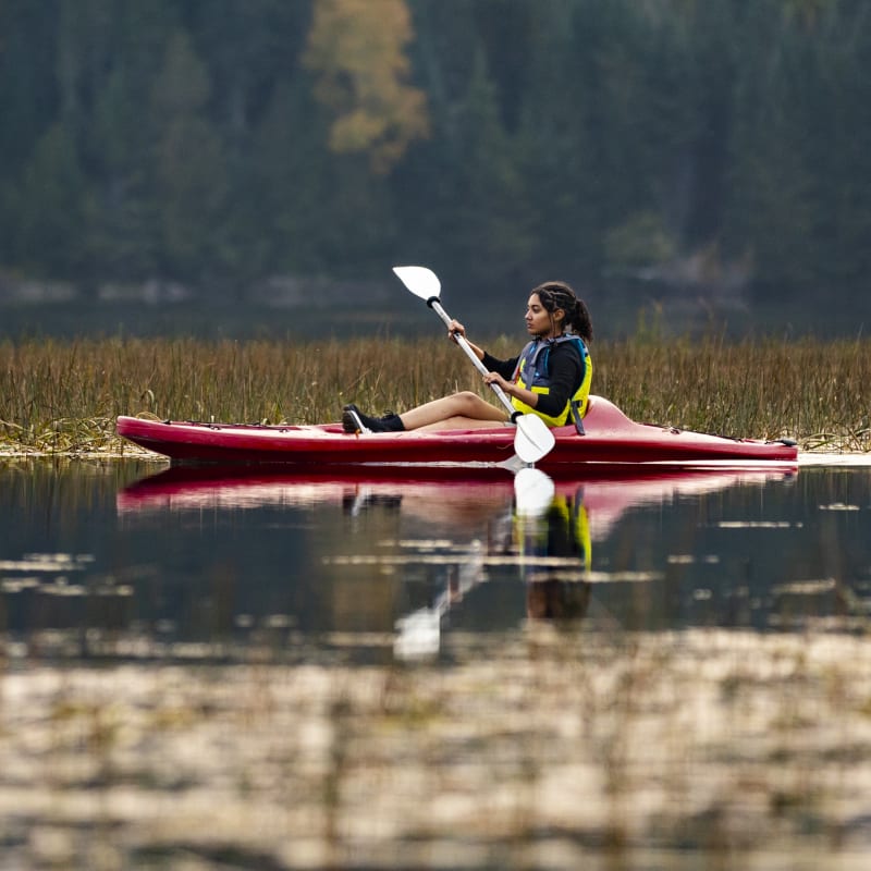 Young woman on a kayak on a lake in the Mont-Tremblant national park in the fall.