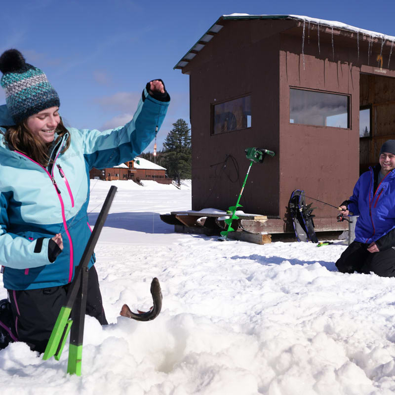 Couple en train de faire de la pêche sur glace par une journée ensoleillée.