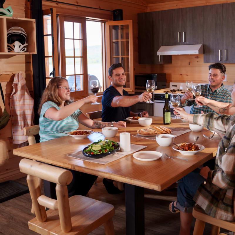 Groupe de convives autour d'une table à l'intérieur d'un chalet en bois.