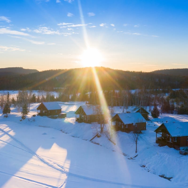 Vue aérienne de chalets sous la neige au bord d’un lac.