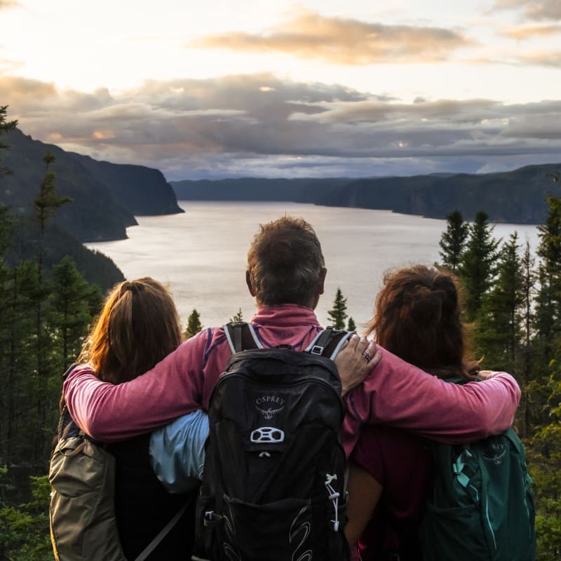 Trois personnes qui admirent le paysage de lac et de forêts.