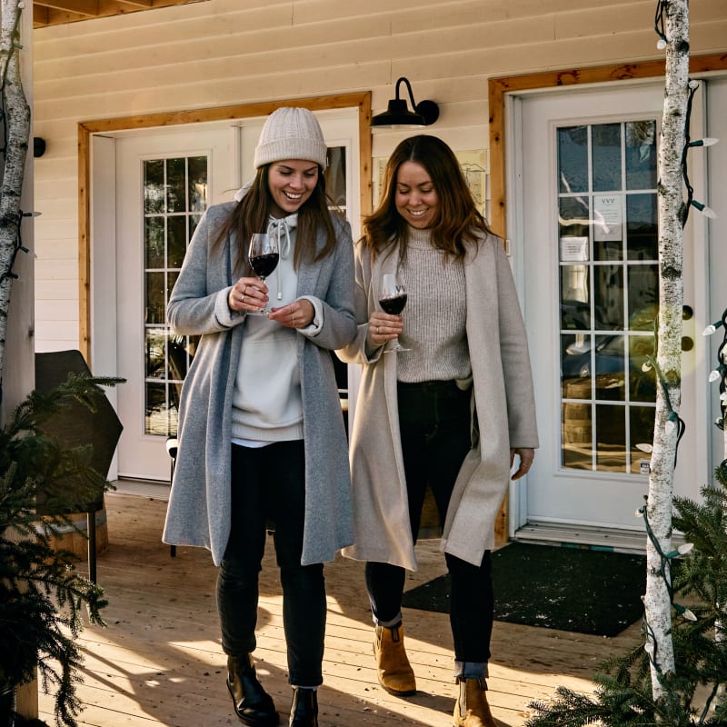 Deux jeunes femmes à l'extérieur d'une boutique sur la propriété d'un vignoble en hiver.