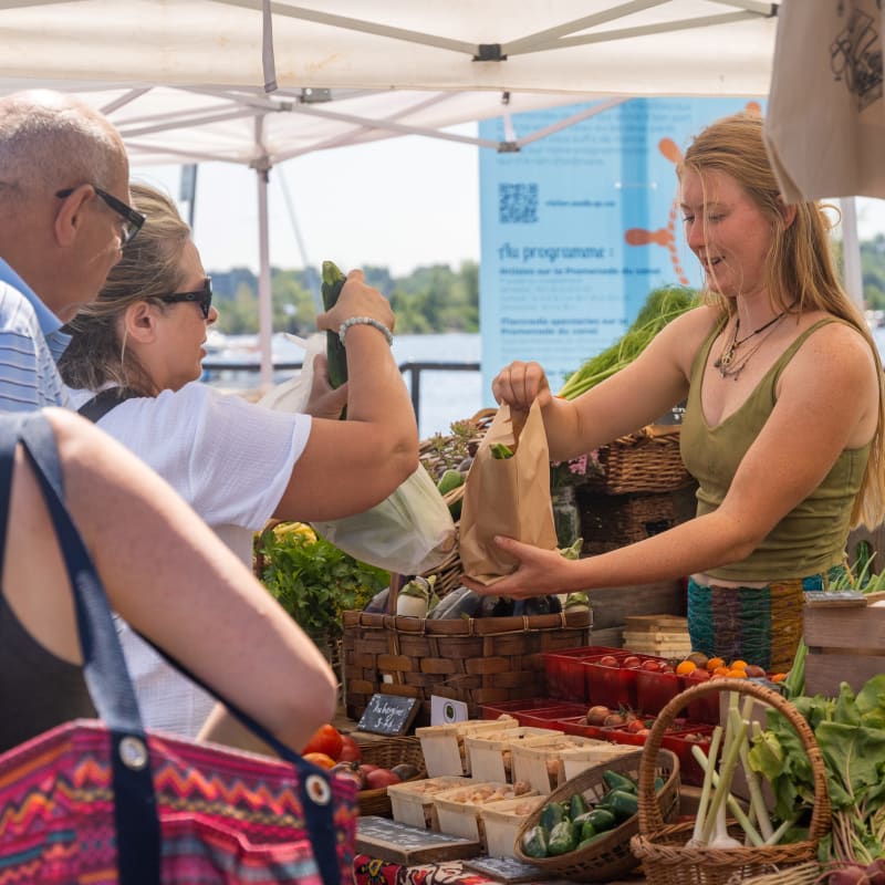 Booth at the farmer's market with customers lined up and merchant.