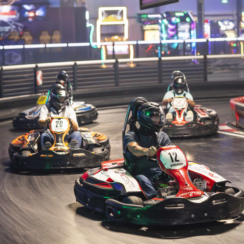 Four people in karts on a racetrack.