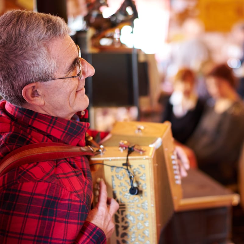 Man in a black-and-red plaid shirt playing accordion.