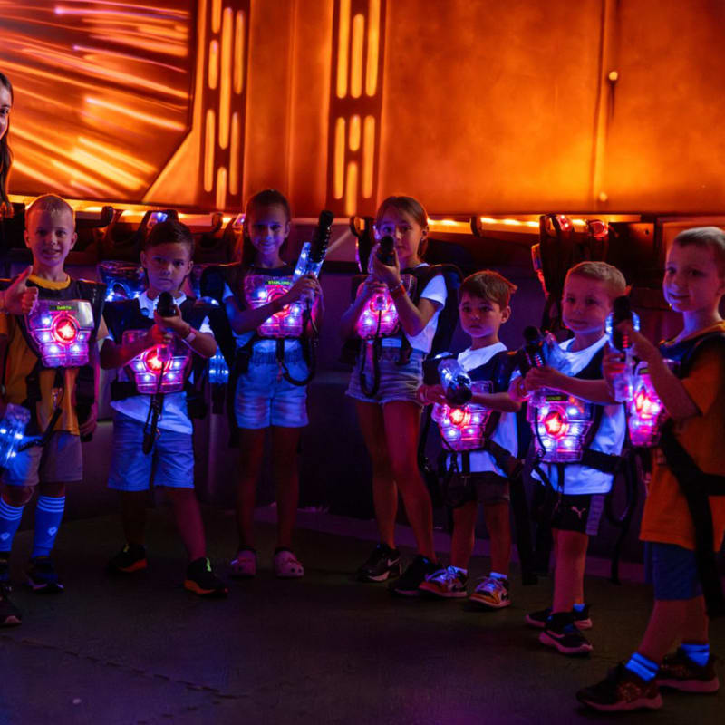 Monitrice avec sept jeunes enfants vêtus de gilets illuminés.
