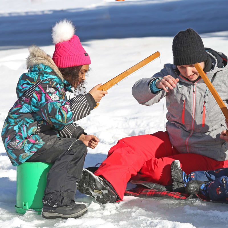 Parent and two kids ice fishing.
