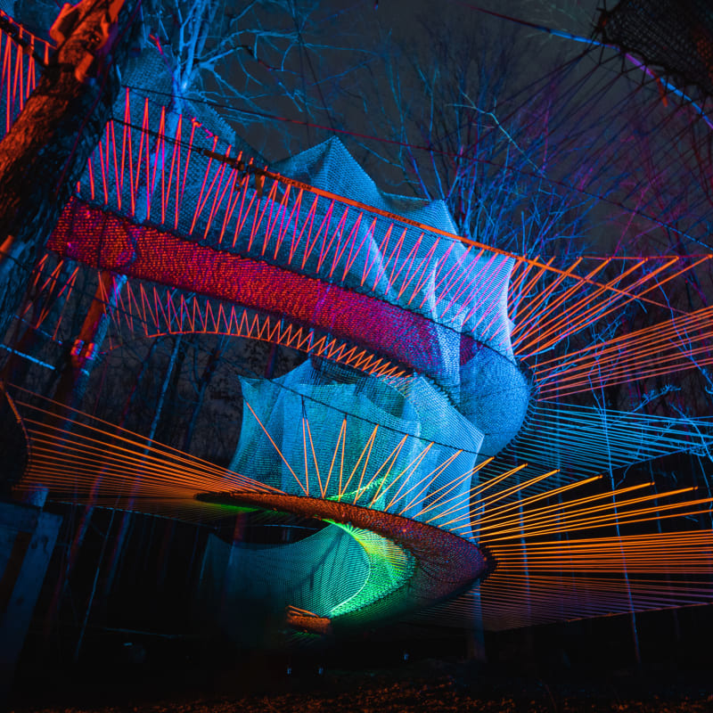 Illuminated trampolines at Upla at night.