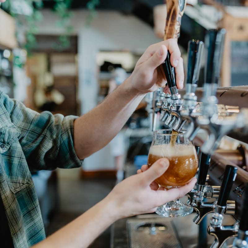 Un barman rempli un verre de bière à la pression.