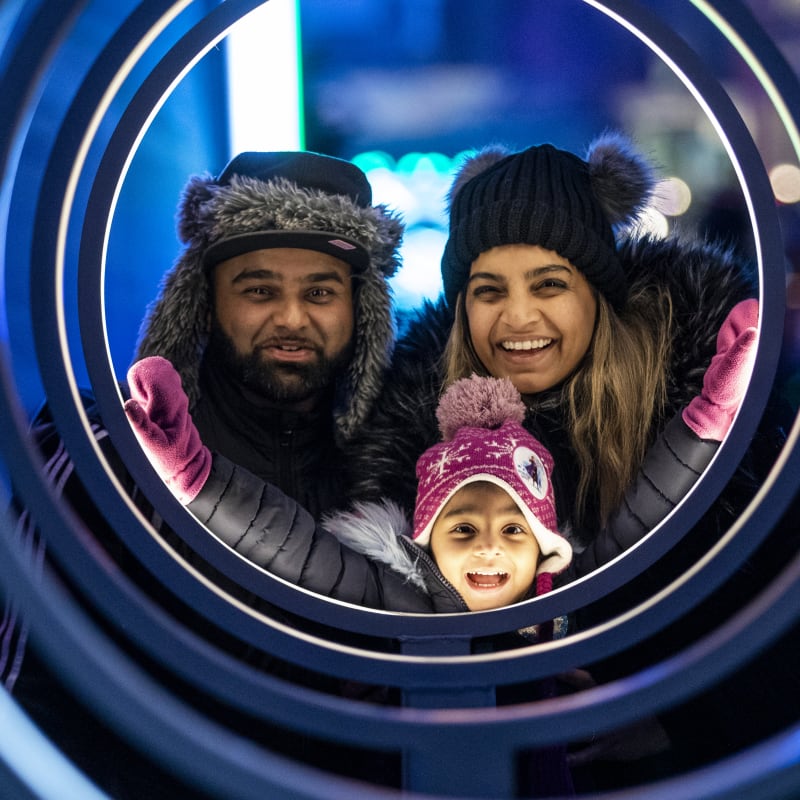 Smiling father, mother and little girl admiring a luminous installation at Winterlude.