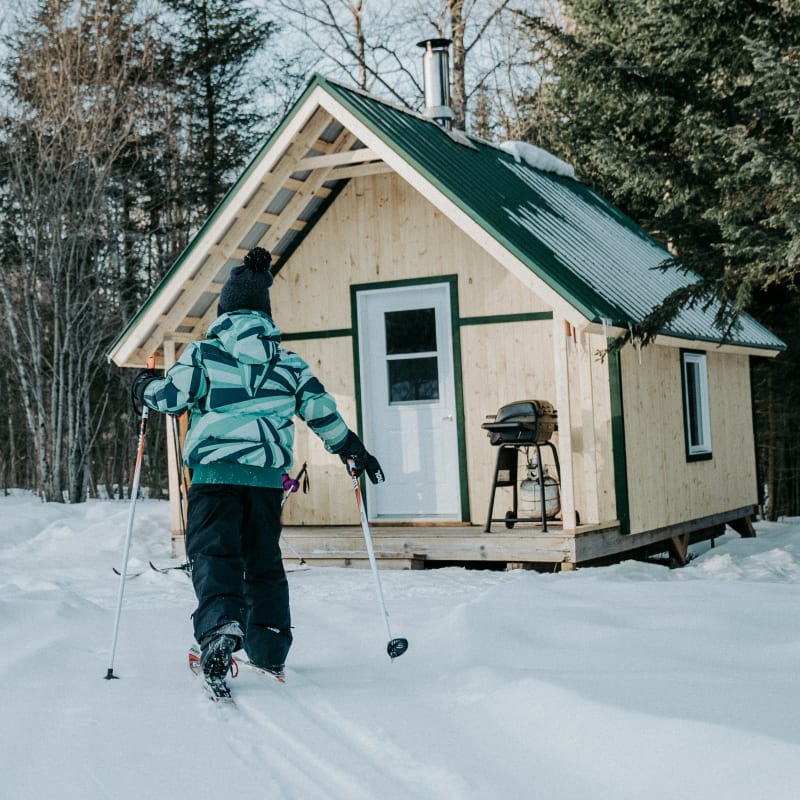 Child wearing skis returning to a cabin.