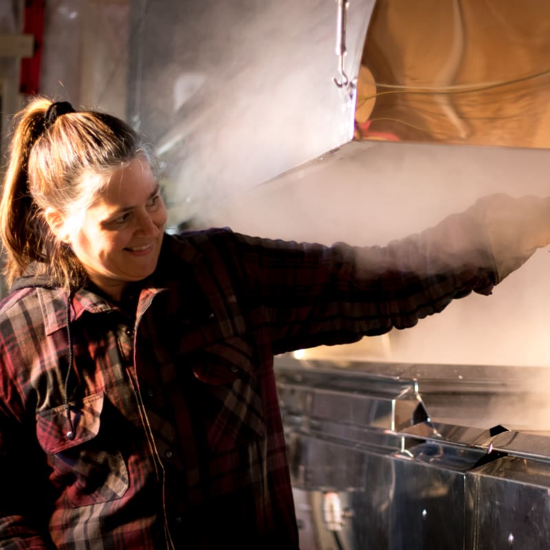 Woman preparing taffy on snow in a sugar shack.