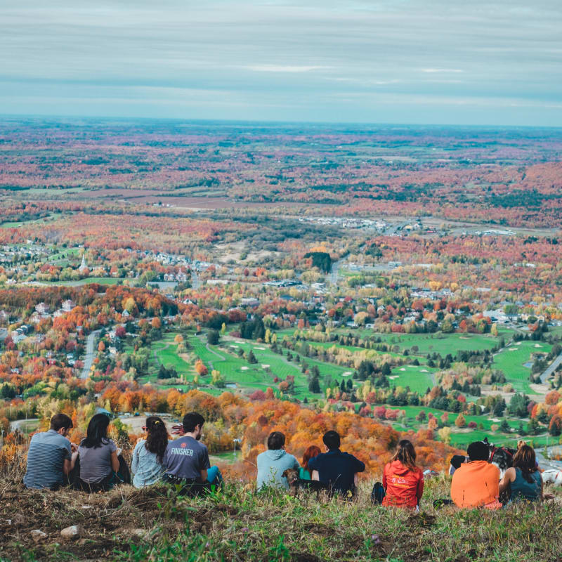Group of people sitting at the top of a mountain in the fall.