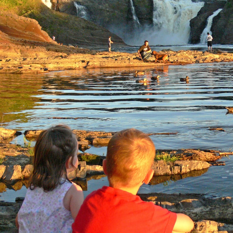 Two young kids sitting by the water at Parc des Chutes-de-la-Chaudière.