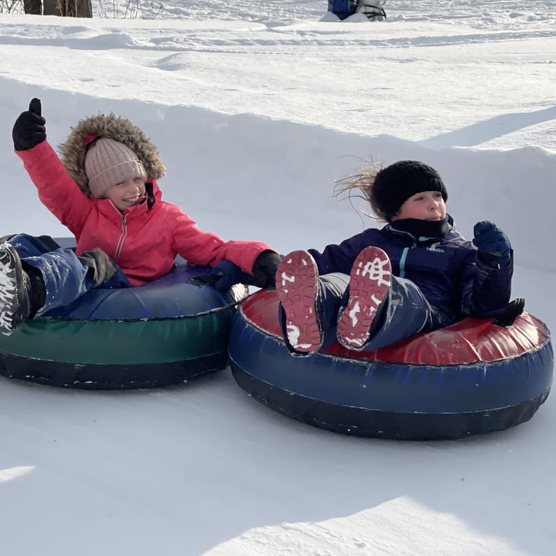 Two children sliding down on tubes.