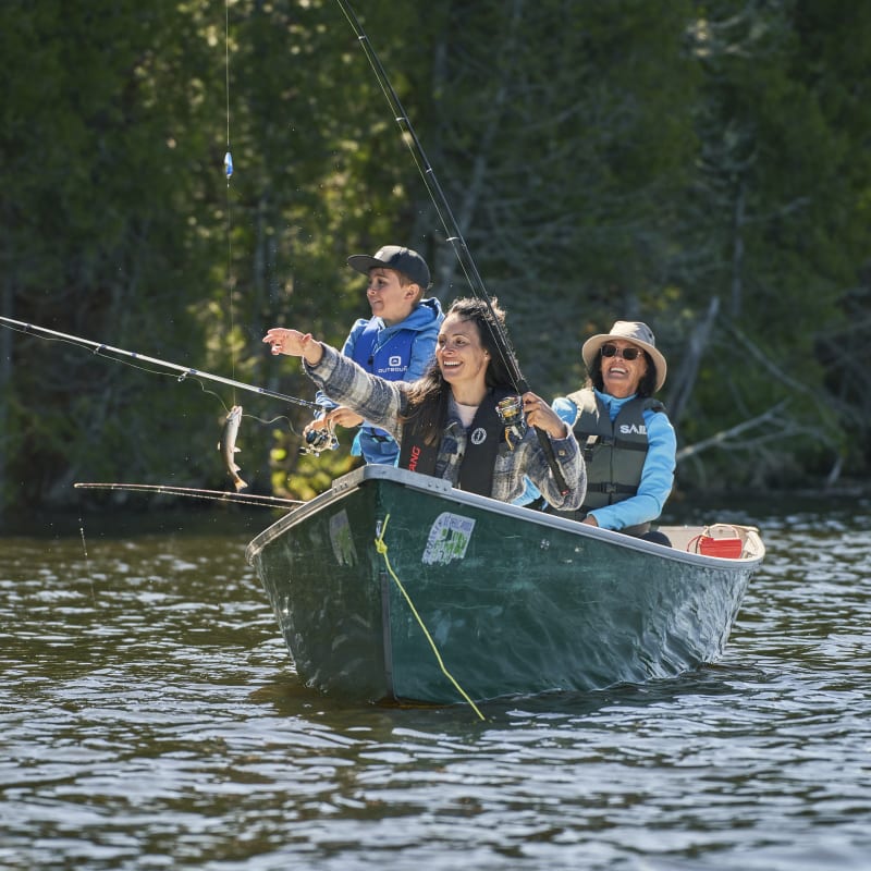 Family fishing in a forest-green fiching row.