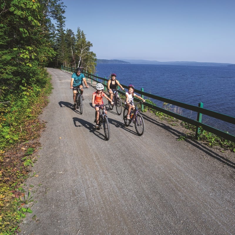 Family of 4 people on bikes by the lake.