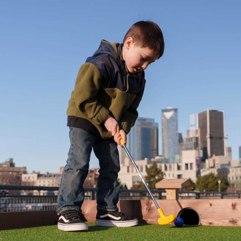 Young boy playing mini-putt