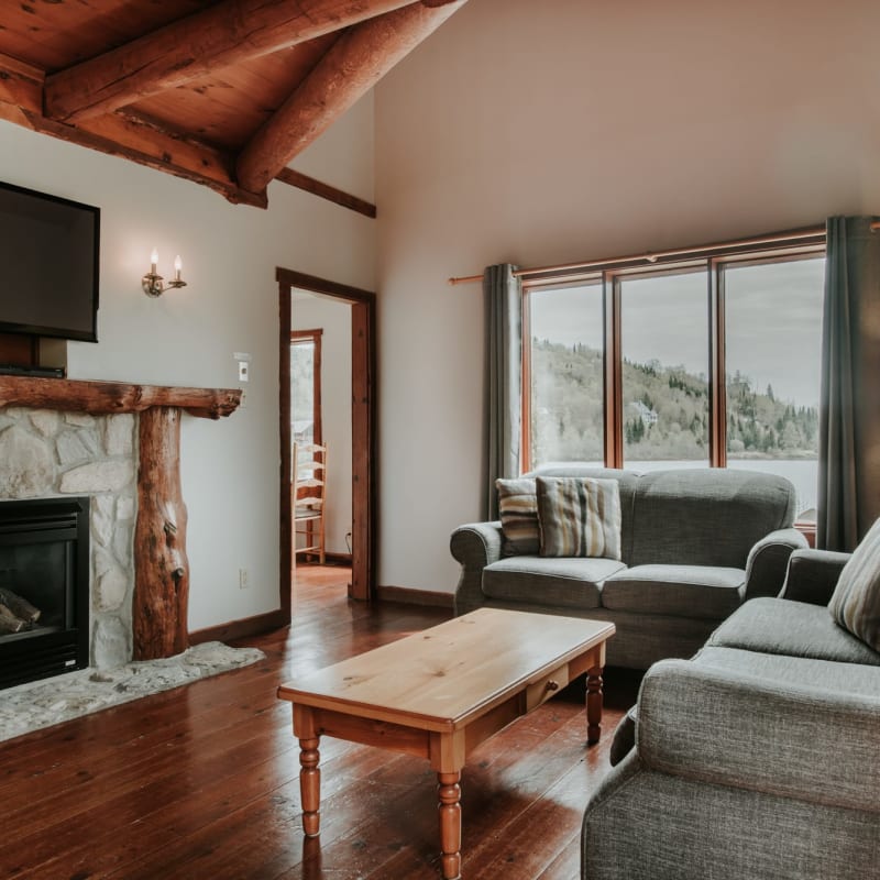 Living room with sofas and a fireplace in one of the Chalets Royal Laurentien.
