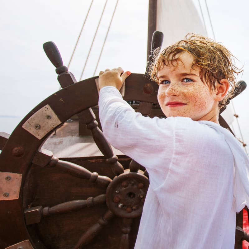 Boy behind the wheel of a ship.