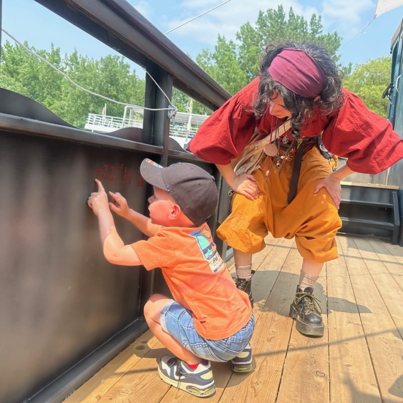 Kid and costumed presenter on a pirate ship.