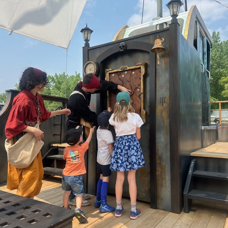 Group of kids and presenters in costumes on a pirate ship.