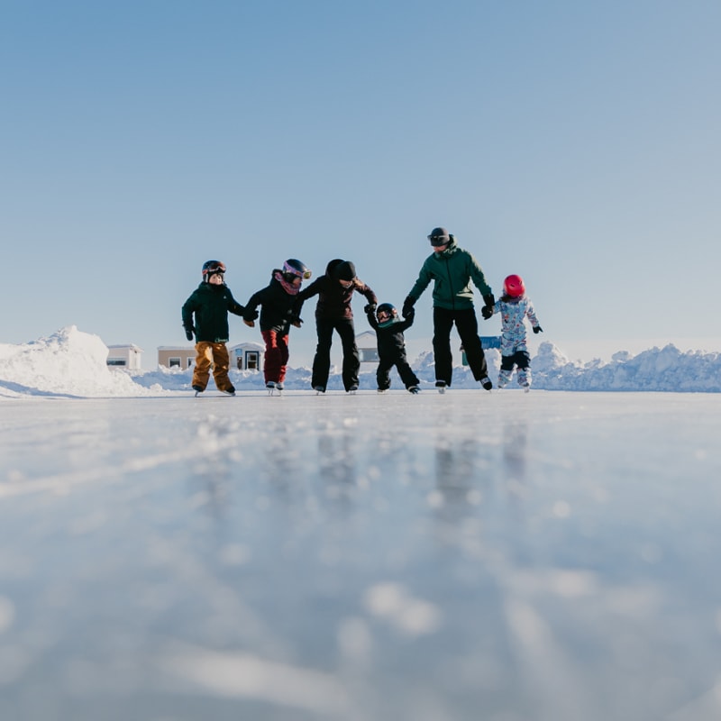 Group of adults and children skating at the Village sur glace.