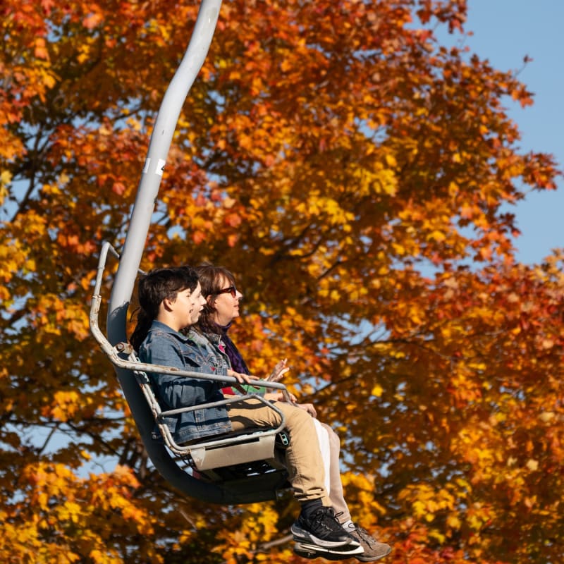 Two adults on a ski lift at Ski Saint-Bruno in the fall.