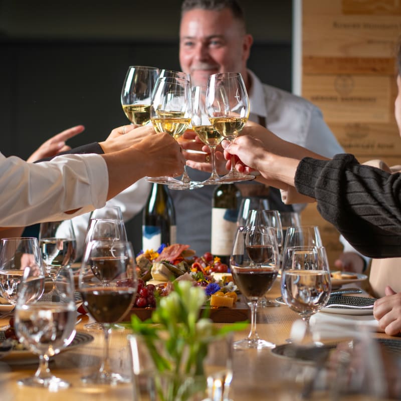 A toast with friends over glasses of white wine.